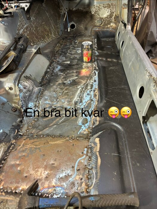 Bilens inre kaross under reparation, svetsade plåtar och en burk med dryck på golvet. Text säger "En bra bit kvar" med emoji.