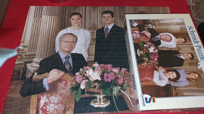 Ett pussel på ett formellt familjeporträtt med en äldre man i kostym sittande framför en blomsterdekoration, med tre personer i bakgrunden.
