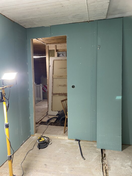 Renovering av övervåningen med nyinstallerade gröna gipsskivor och byggmaterial på golvet.