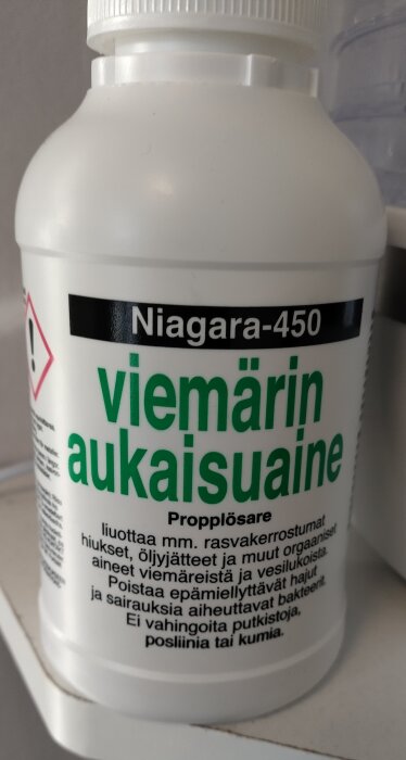 Förpackning av Niagara-450 propplösare med varningstext och etikett på finska. Används för att lösa upp fett och organiska material i avlopp.