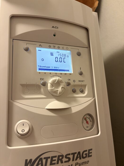 Värmepumpsdisplay som visar 0,0°C tilloppstemp, inställningsknappar och en tryckmätare med "Waterstage" logotyp.