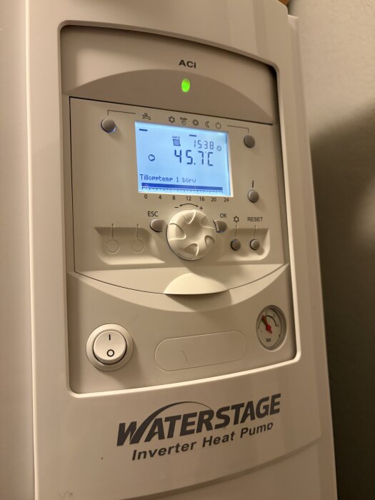 Värmepumpens kontrollpanel visar en temperatur på 45,7°C, med skärm och knappar för inställning, logotypen "Waterstage Inverter Heat Pump" synlig.
