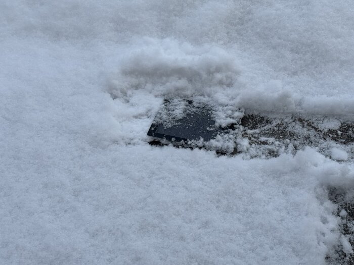 Enheten ligger i snön efter 13 år av användning, för säkerhet. Snön täcker delvis enheten mot en vinterbakgrund.