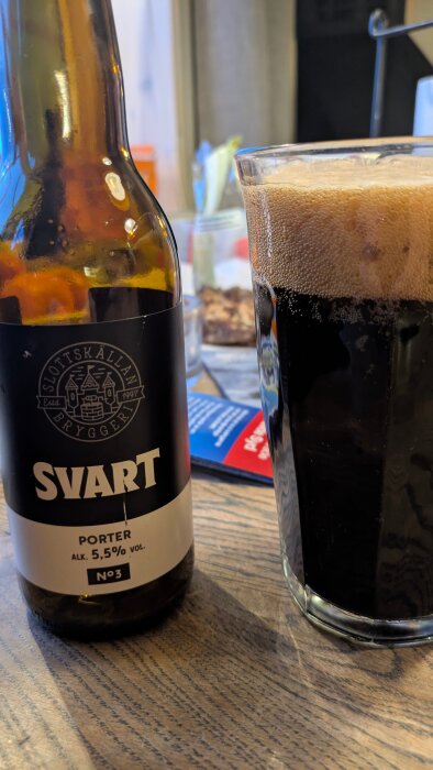 Flaska och glas med Svart porter på ett bord inomhus.