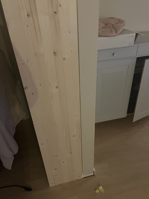 Bokhylla byggd mot valv, med fokus på utrymmet för fogning mellan bokhyllan och väggen. Syns även en del av ett skåp och golv.