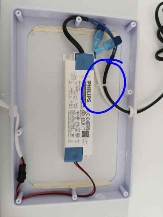 Inre vy av en elektrisk enhet med svarta och vita kablar anslutna till en Philips LED-drivare.