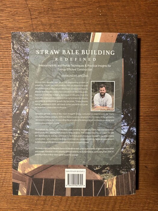 Baksidan av boken "Straw Bale Building: Redefined" med text om energisnålt byggande av höhus och författarporträtt i hörnet.
