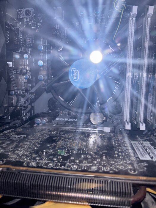 Datorens insida med synligt moderkort MSI B250 Bazooka och Intel-processor, med fokus på komponenter som grafikkort och kylfläkt.