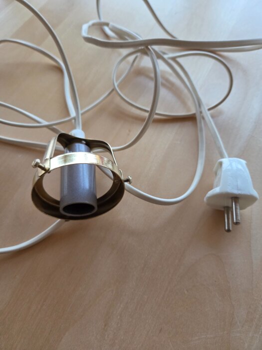 Äldre lampdel med ojordad kabel och stickkontakt på ett bord.