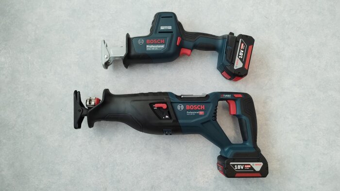 Två Bosch Professional tigersågar, modellerna GSA 18V-24 och GSA 18V-28, ligger på en grå yta, båda med batteripack monterade.
