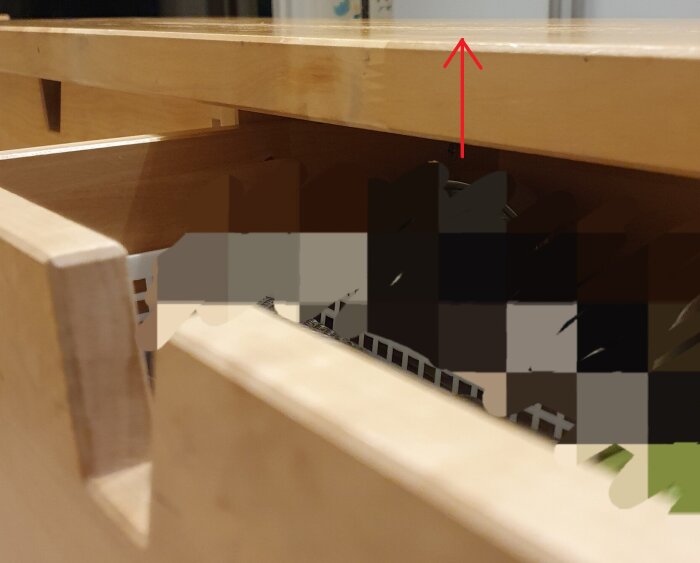 Närbild av en trälåda under en bänkskiva, pil pekar mot bänkskivan ovanför.