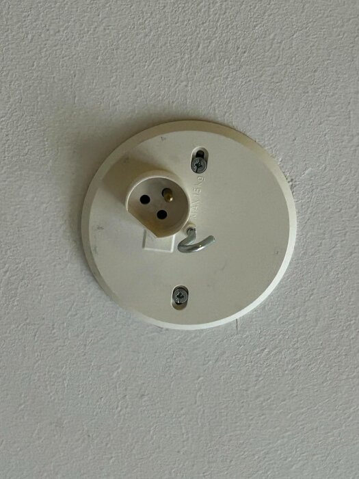 Närbild av ett tvåpoligt vägguttag med en stickpropp ansluten i ett spekulerande foruminlägg om adaptrar och proppbyte för en gammal lampa.