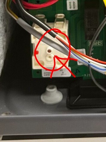 Elektronisk komponent med kablar, vit kontakt och en markerad röd knapp inuti en apparat, för felsökning och återställning av fläkt.