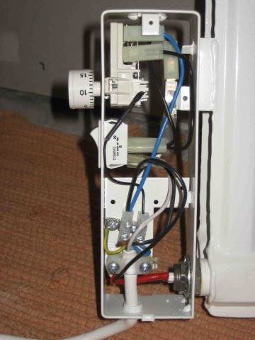 Elradiator med synlig intern kabeldragning och termostat, placerad på en beige matta.