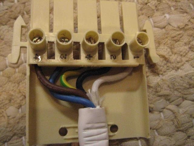 Elektrisk anslutningsplint med fem kopplingspunkter och flera färgade kablar, inklusive brun, blå, grön/gul, svart och vit.