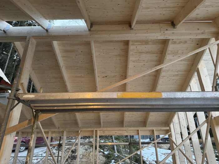 Trästomme av ett tak under byggnation med stöttande ställning på en byggarbetsplats inför dåligt väder.