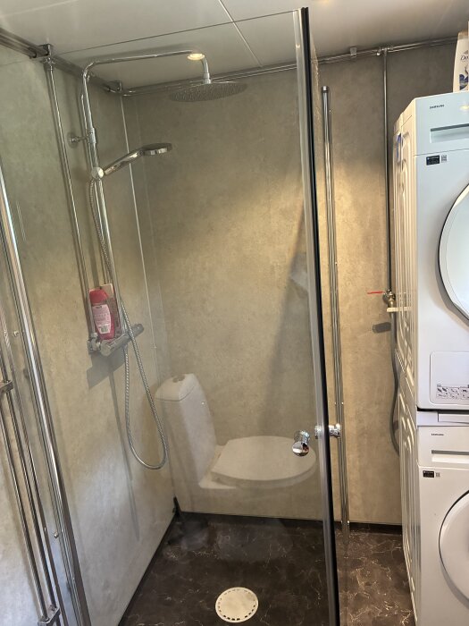 Badrum med duschhörna, fibo våtrumsskivor, våtrumsmatta och kombinerad tvättmaskin samt torktumlare.
