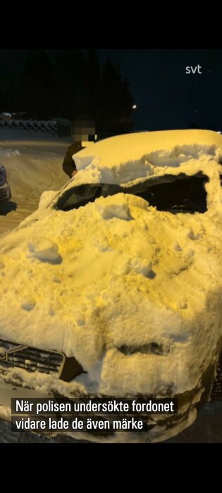 Bil täckt av snö på tak och framruta, nattmiljö. Textruta beskriver polisupptäckt.