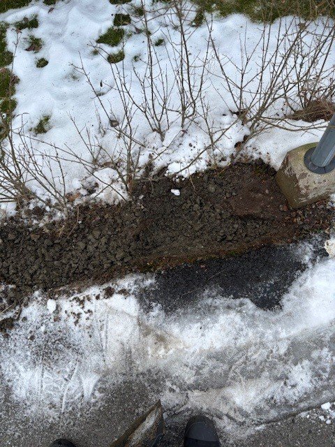 Grävd mark under snötäcke där kabelkanal förbereds för installation av laddstolpe vid parkeringsplats, enligt ritning i BRF.