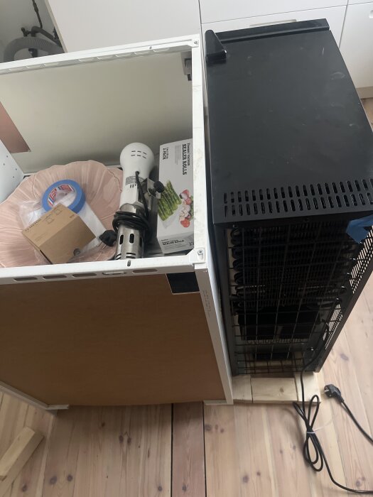 Ikea Metod köksmodul och vinkyl placerad på träram, köksutrustning och en kartong syns inuti modulen.