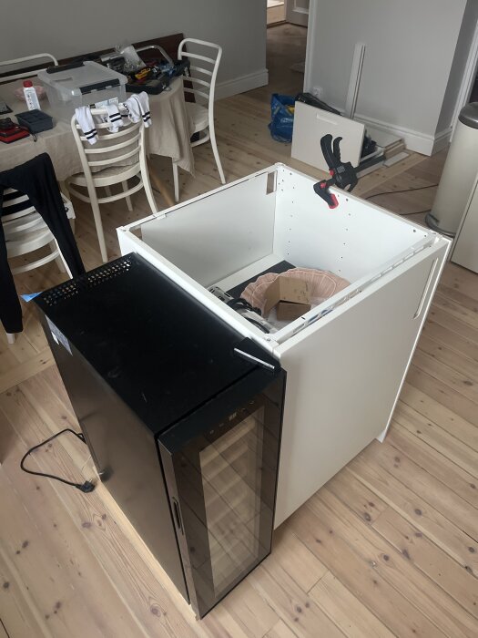 Ikea Metod köksdel med svart vinkyl, delvis monterad, träparkettgolv, verktyg och material på bord i bakgrunden.