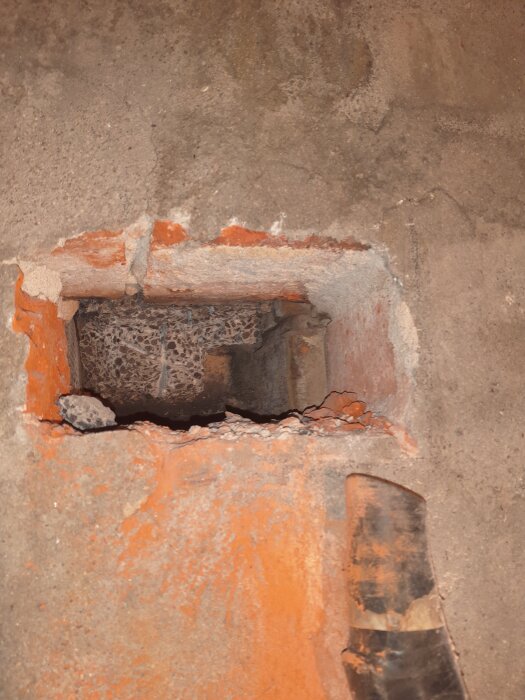 Hål i betong som visar lecakulor, delvis igenmurat. Före bild av pågående byggprojekt.