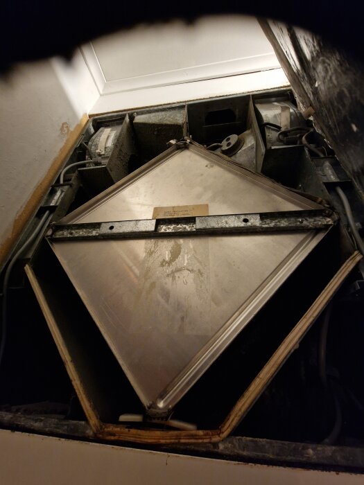 En ventilationsenhet med ett öppet metallhölje, där ett filter syns på höger sida, i behov av rengöring och byte.