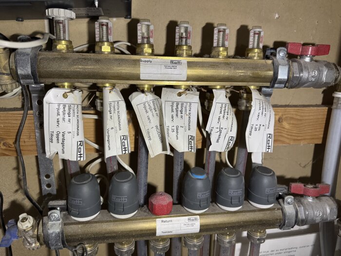 Värmesystem med rör och termostater där en termostat har en blå ring; övriga komponenter märkta med information för retur och tillopp.