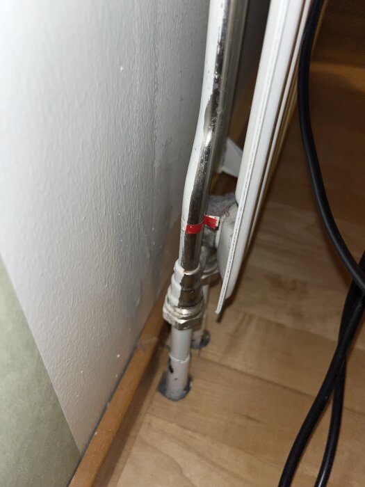 Radiatorrör med röd markeringsremsa vid anslutning till golv, problem med ojämn värmefördelning i elementet.