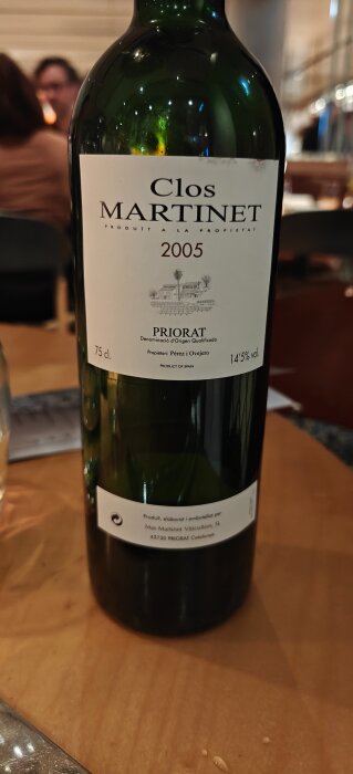 Flaska med Clos Martinet rödvin från 2005, Priorat-regionen i Spanien, placerad på ett träbord.