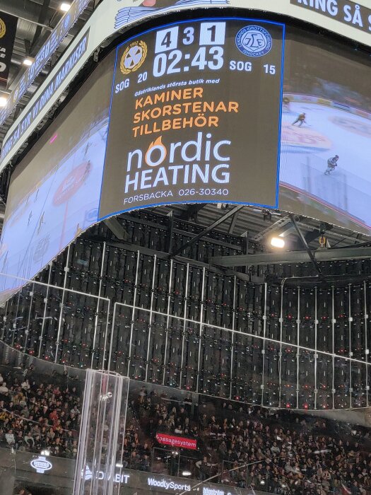 Hockeymatch med stor jumbotron som visar ställningen 4-1 och reklam för Nordic Heating, publik i bakgrunden.