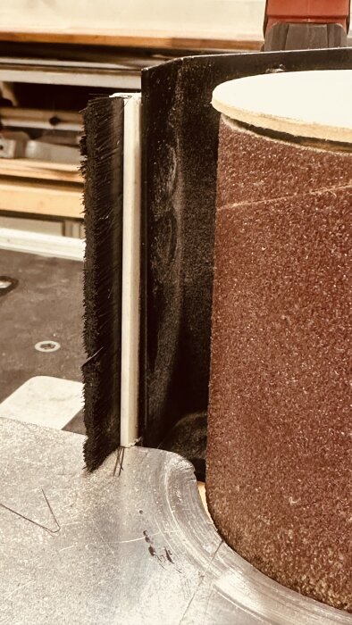 Närbild av en garrotterings-jigg med verktygsrulle och borste, detaljer för förbättrad användning visas.