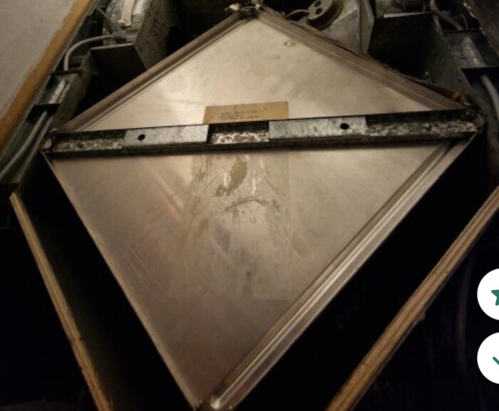 Ruterformad plattvärmeväxlare med metallhandtag, förberedd för rengöring enligt instruktion.