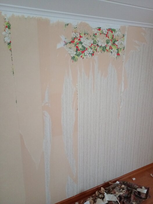 Vägg under renovering med borttagen tapet ovanför blomstrande tapet.