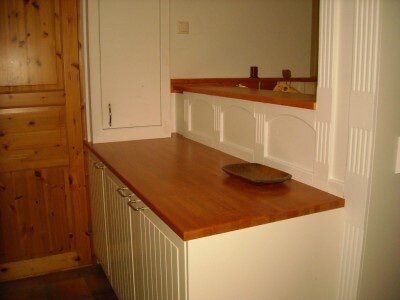 Kök med träbänkskiva och bröstpanel i sekelskiftesstil, med vit panel och trädetaljer.