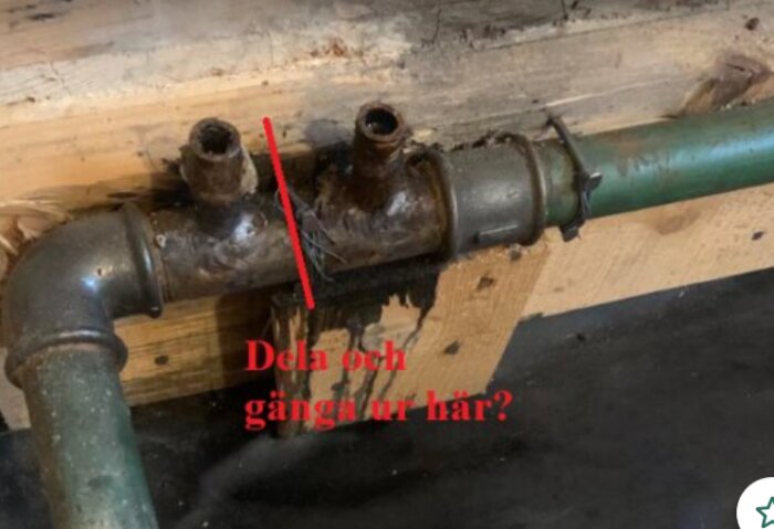 Rostiga rörkopplingar under golv, med en text "Dela och gänga ur här?" markerat i rött på bilden.
