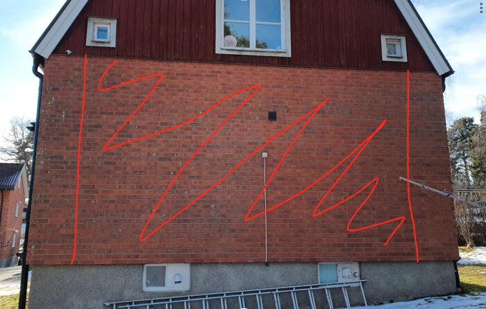 Tegelvägg på ett hus med röda linjer ritade över fasaden, en stege står lutad mot grunden, och två små fönster syns i överkant.