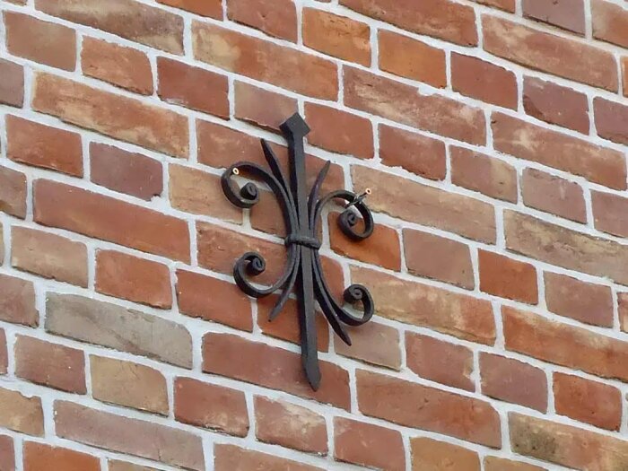 Decorativ väggankare monterad på tegelfasad.