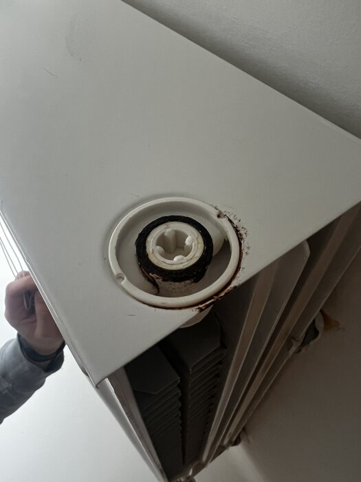 Radiator med rostig bottenplugg och plastbit med stora spår synlig.