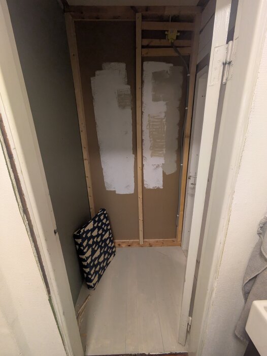 Renovering av ett badrum med exponerad trästomme och vitmålade ytor, förberett för installation av dusch i ett hus.