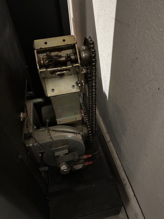 Pelletsmatarskruv med kedja och motor i en Ecotec tyr från 2004 installerad i ett hus, visad från sidan.