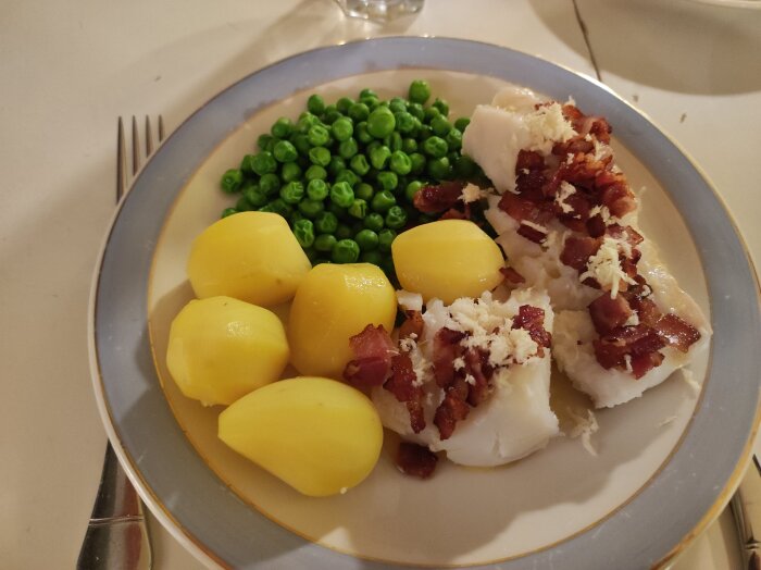 Tallrik med kokt potatis, ärtor och fisksfile toppat med bacon och pepparrot.