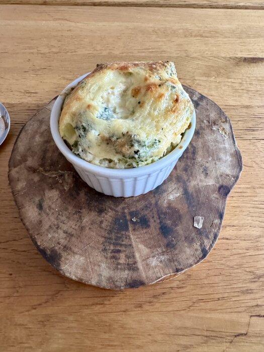 Ost- och broccolisufflé serverad i en rund gratängform på ett rustikt träunderlägg.