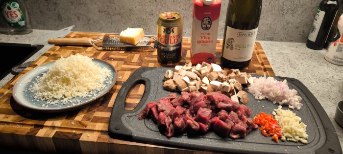 Ingredienser för oxfilépasta, inklusive strimlad oxfilé, svamp, lök, grädde, Rieslingvin och ost på en skärbräda och bänk.