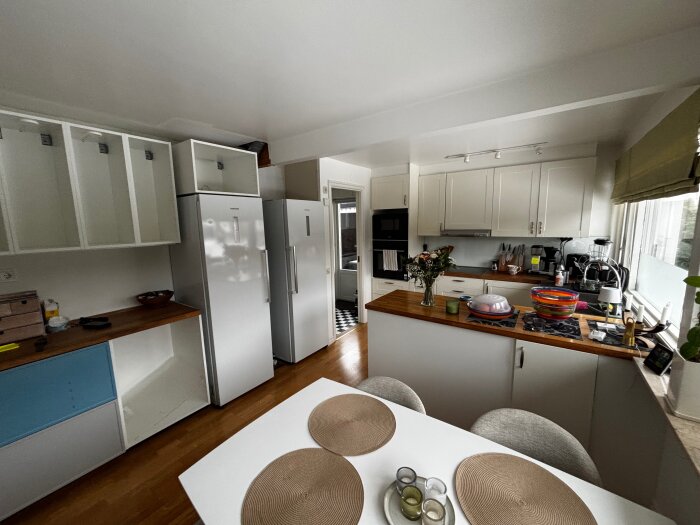 Modernt kök med IKEA METOD ljusgrå skåp, vitvaror och bänkskiva i marmorlook. Ekparkettgolv och kaffestation med vitrin- och bänkskåp.