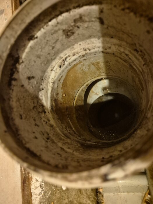 Inuti ett gammalt, rostigt rör som ska ersättas för en renovering av toaletten. Rörets yta är smutsig och sliten.