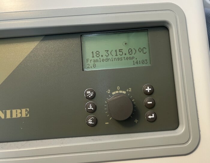 Bild på Nibe värmesystem, display visar aktuell och önskad temperatur, inställningsratt och knappar synliga.