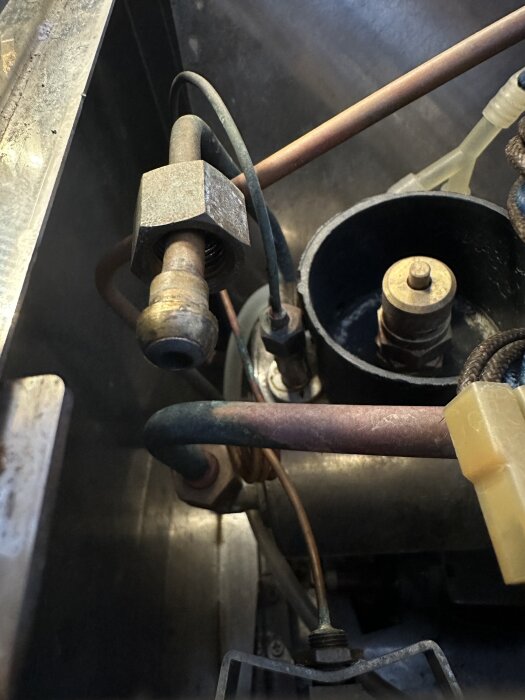 Kaffemaskinens inre med fokus på ångrör, kopplingar och en mutter; ångröret har en invändig gänga, visas i ett metallfärgat område.