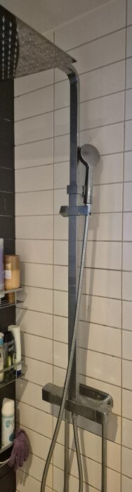 Duscharmatur med takdusch och handdusch monterad på kakelvägg i badrum.