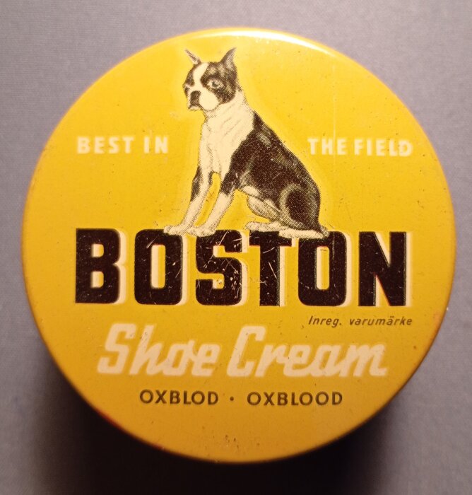 Gul burk med text "Boston Shoe Cream Oxblood", illustration av en hund på locket.